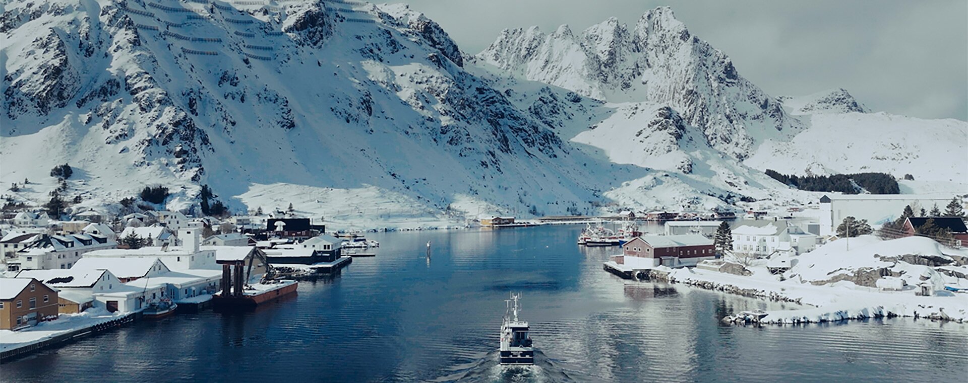 Vinterlig innseiling til nordnorsk fiskevær med båt på tur inn