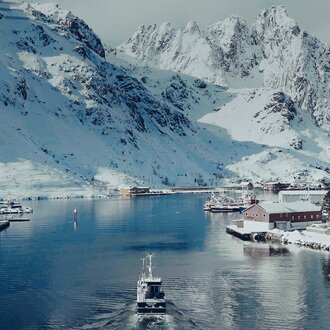 Vinterlig innseiling til nordnorsk fiskevær med båt på tur inn