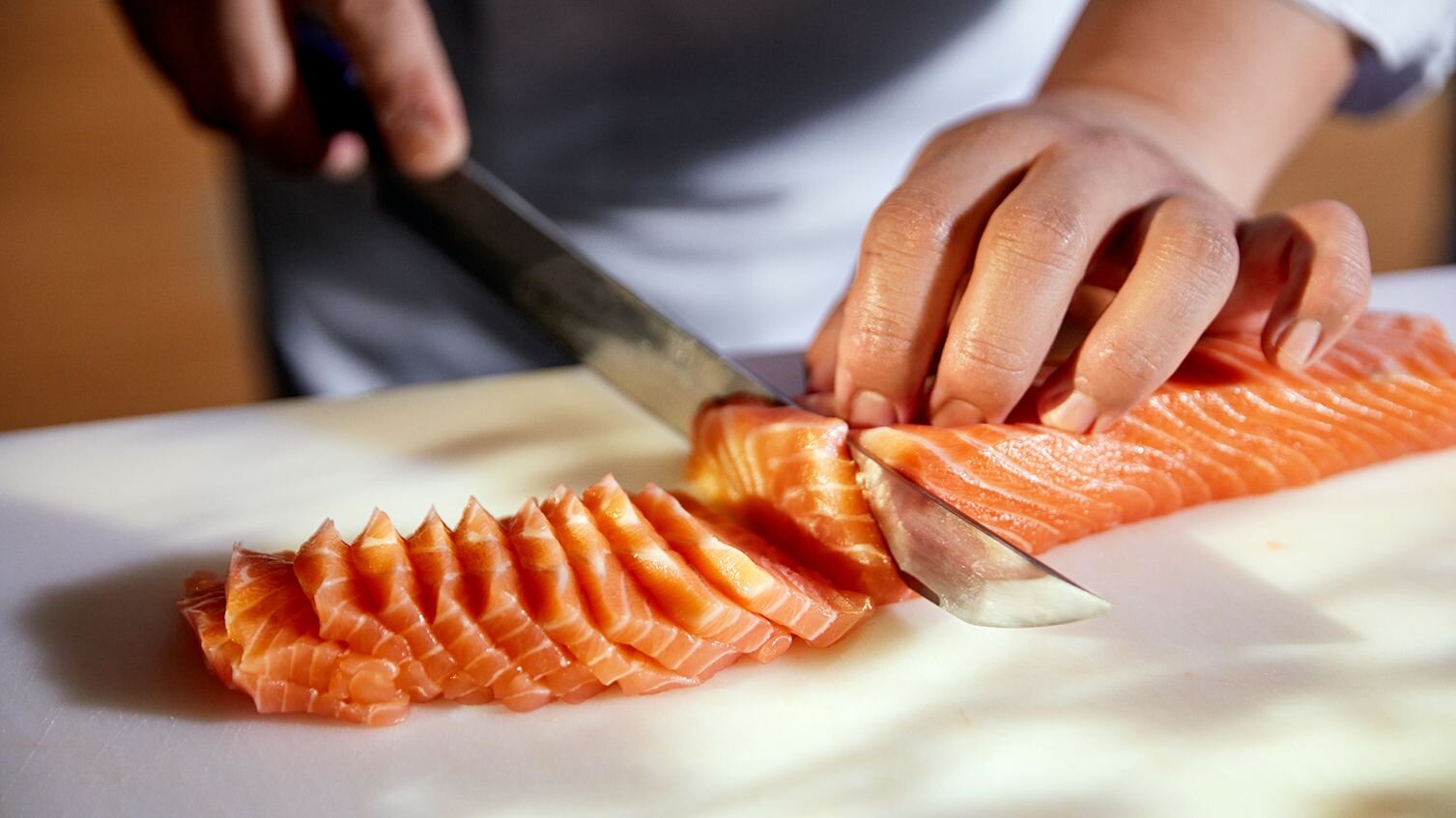 Sushikokk som kutter opp norsk laks til sashimi.