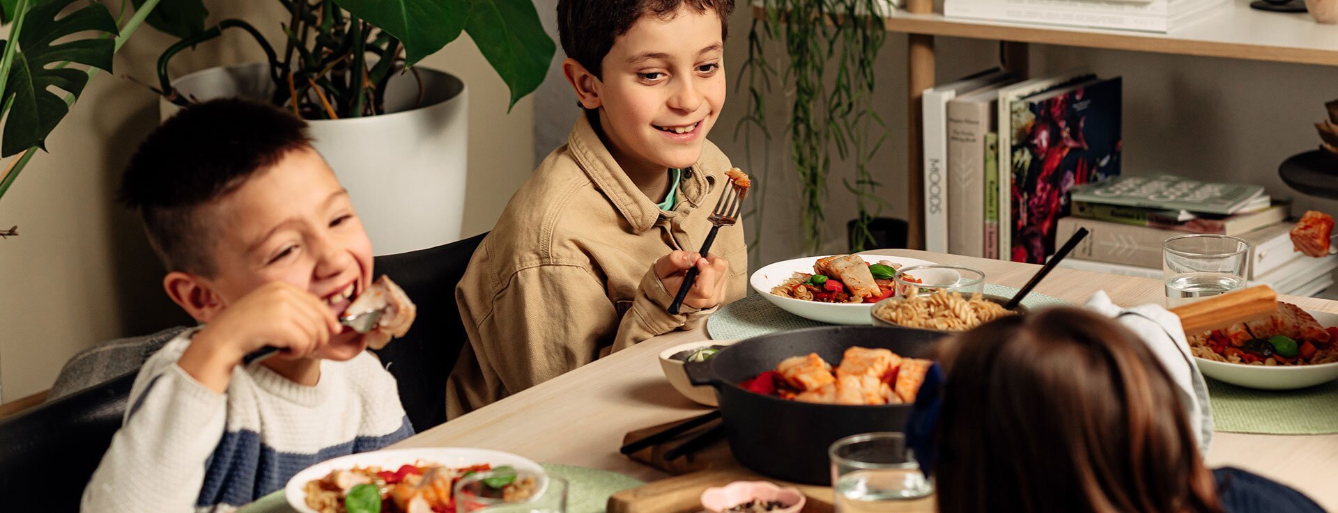 Barn ved spisebord som spiser fiskegryte med tomat