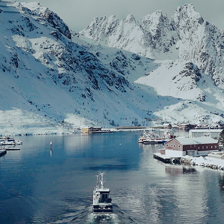 Vinterlig innseiling til nordnorsk fiskevær med båt på tur inn
