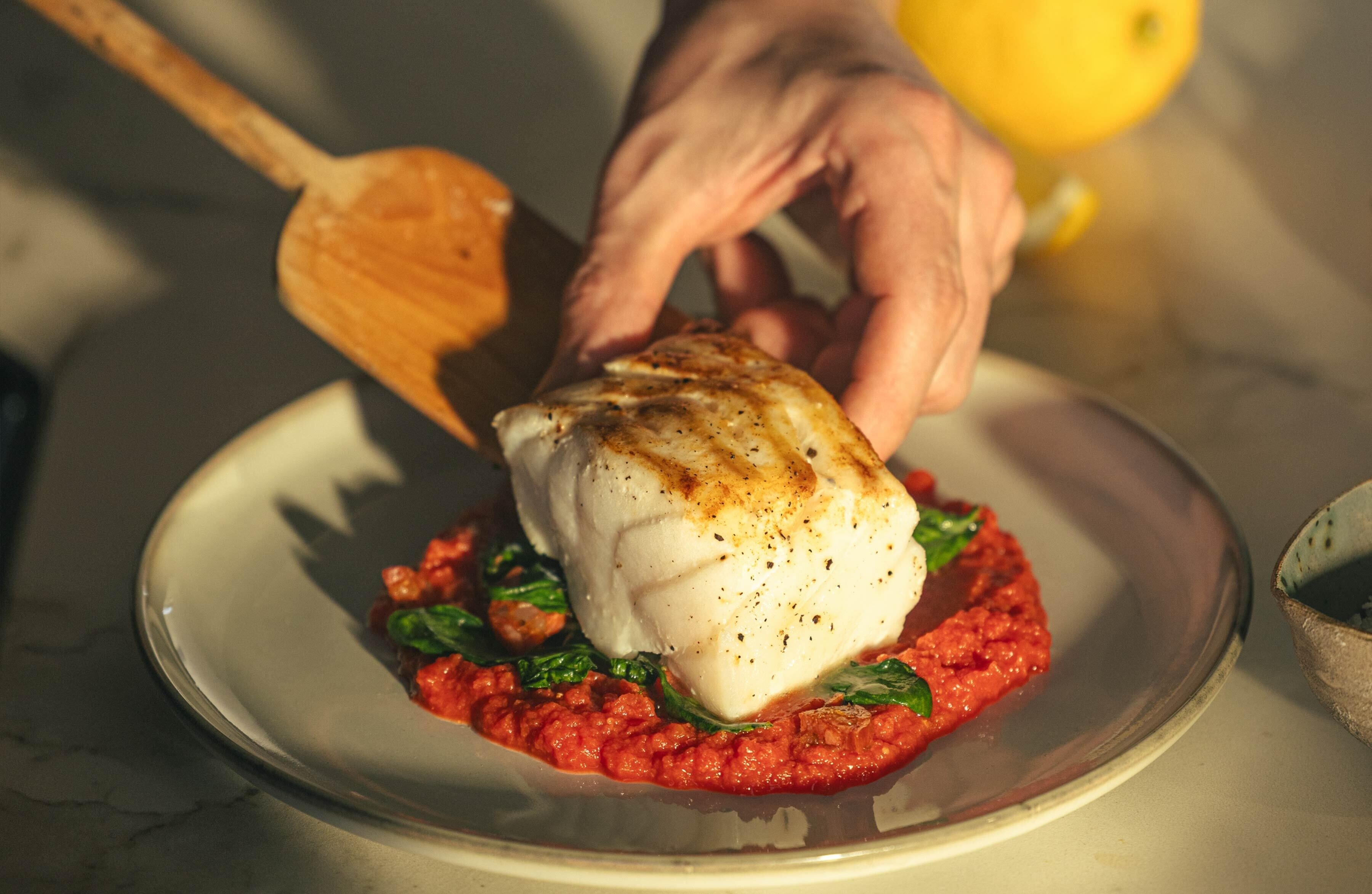 Filet of white fish being plated. 