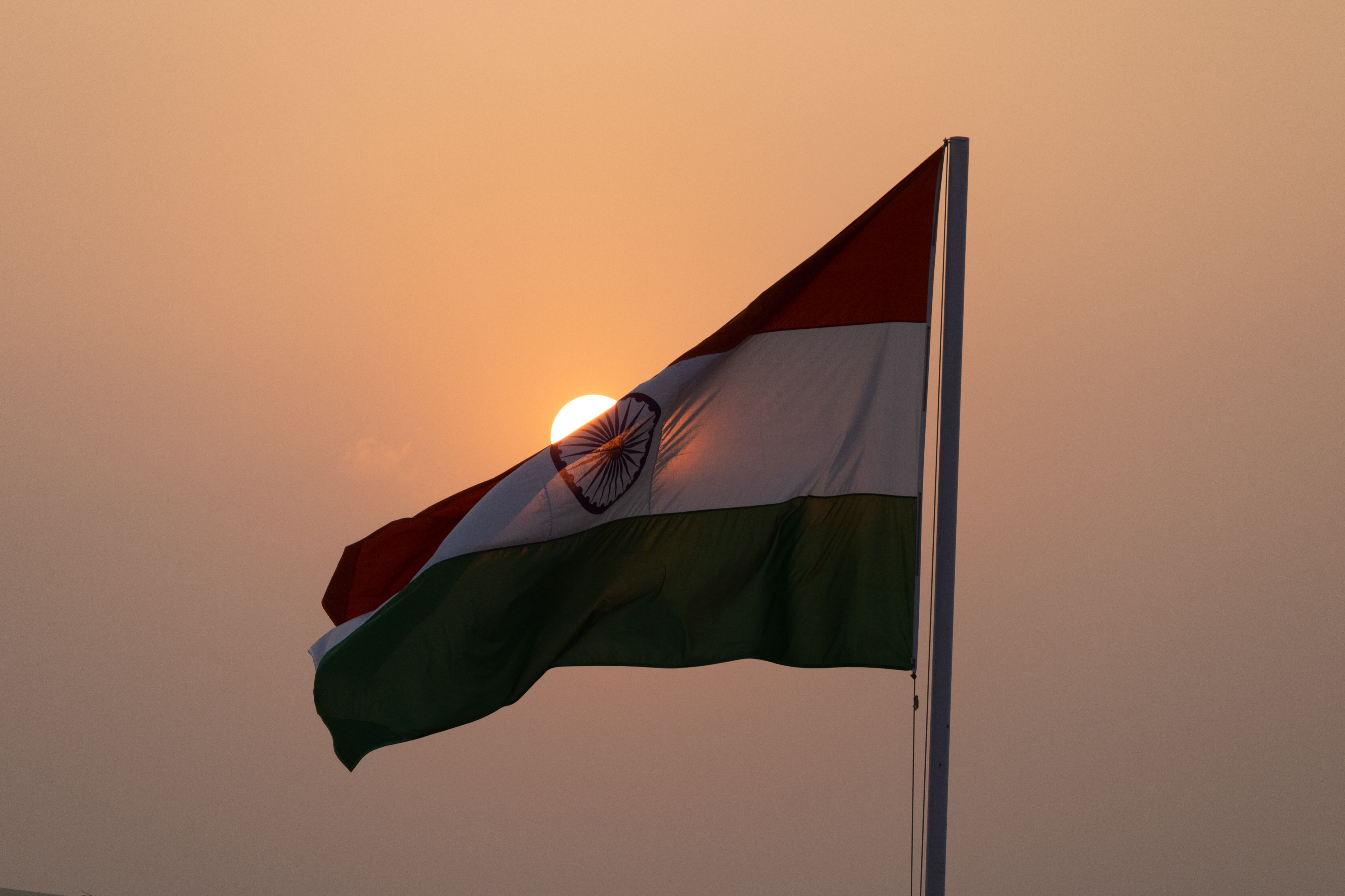 Alt text: Indias flagg vaier mot en oransje kveldshimmel